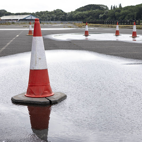 An empty parking lot with traffic cones and puddles
