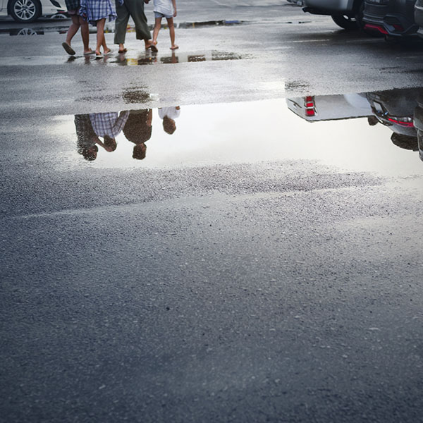 Wet parking spaces after hard rain fall with reflection in puddle on the ground.Selective focus.