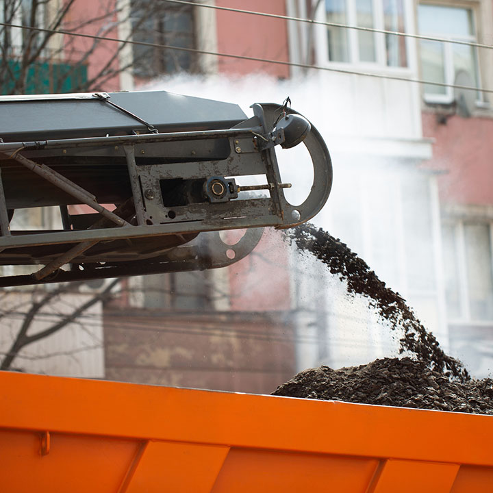 Road milling machine removes old asphalt and loads milled asphalt into the dump truck.